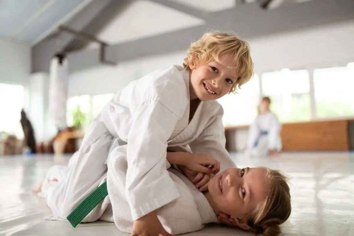 Kids practicing martial arts grappling on training mats during class